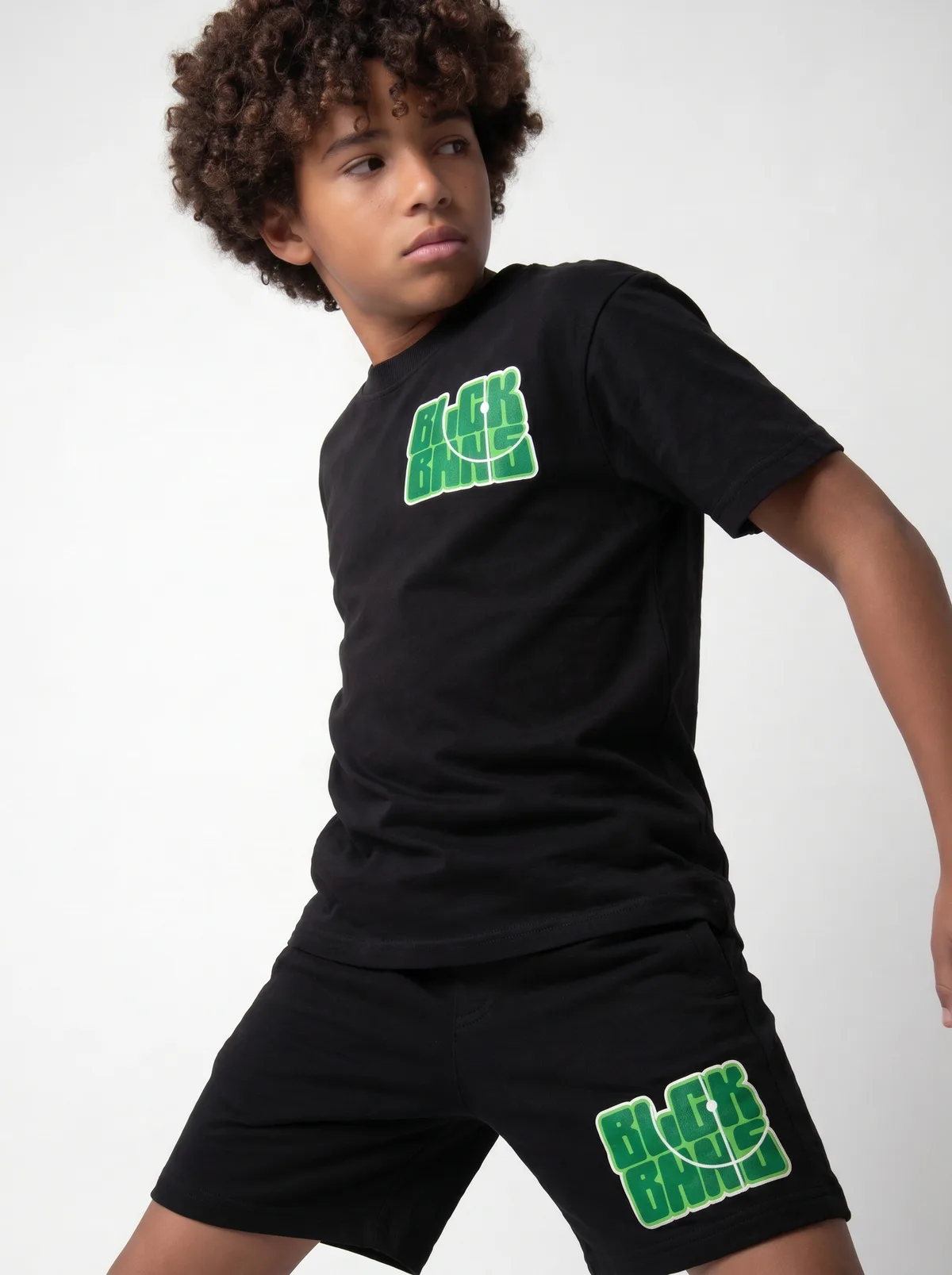 Black Bananas black BLCK BNNS green-print tee chest detail crop showing rounded green graphic on AI young model in clean white studio