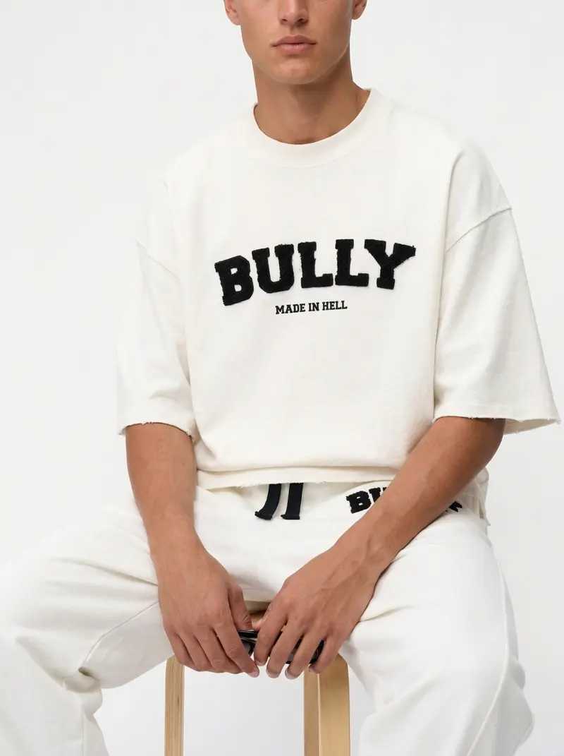 Bully Made In Hell cream co-ord set, seated editorial pose on a stool