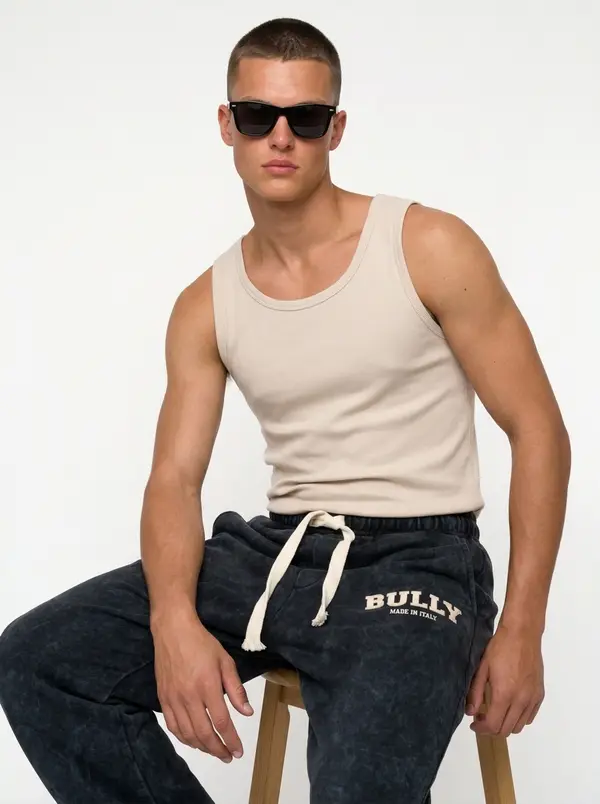 Bully ink acid-wash sweatpant, seated editorial pose with a ribbed tank