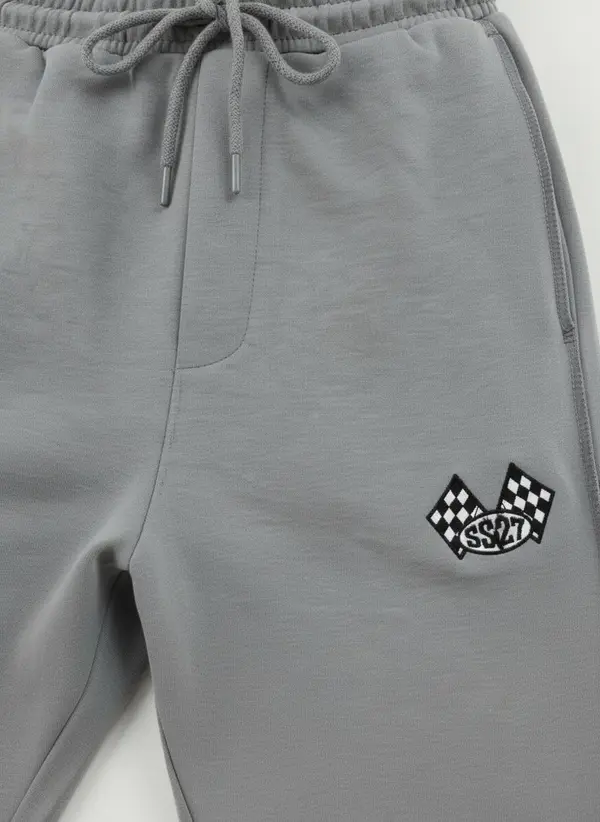 Bully silver checkered-flag sweatpant hip detail macro showing the chequered flag embroidery