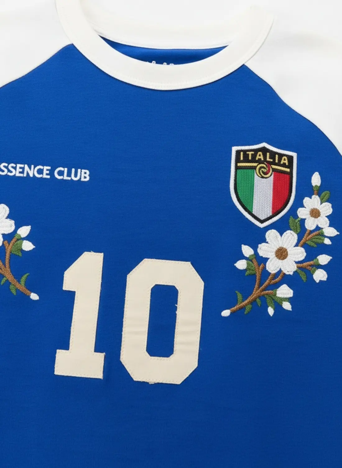 Bully Essence Club raglan tee chest detail macro showing the Italia crest, appliqué number 10 and embroidered floral sprays