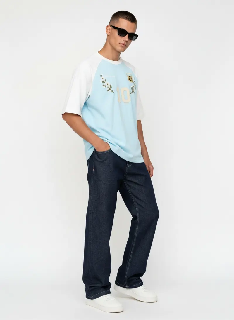 Bully Essence Club raglan tee in sky blue with white sleeves and an embroidered Argentina-style crest, on an AI male model