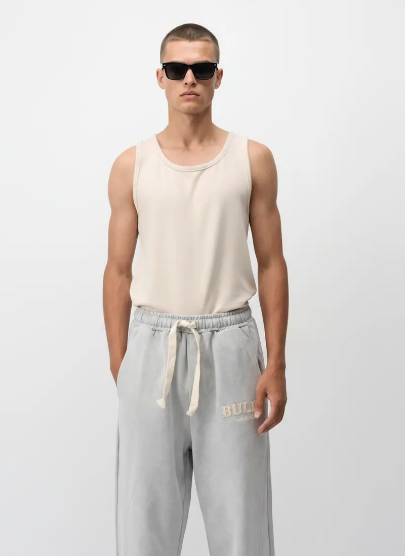 Bully wordmark sweatpant in heather grey with a ribbed tank, on an AI male model in a bright white studio