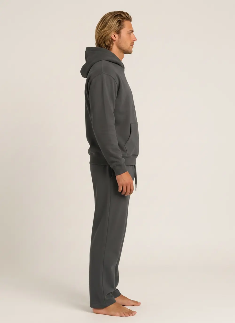 Future Homme graphite hoodie and jogger set, side profile full length, on an AI male model in a warm neutral studio