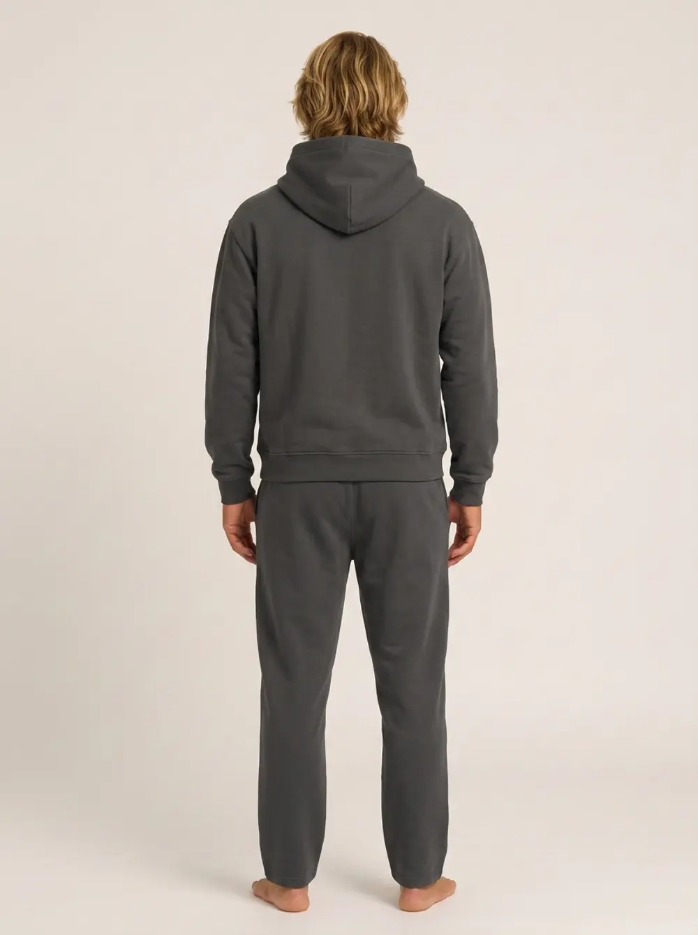 Future Homme graphite hooded set, back full-length with hood up, on an AI male model in a warm studio