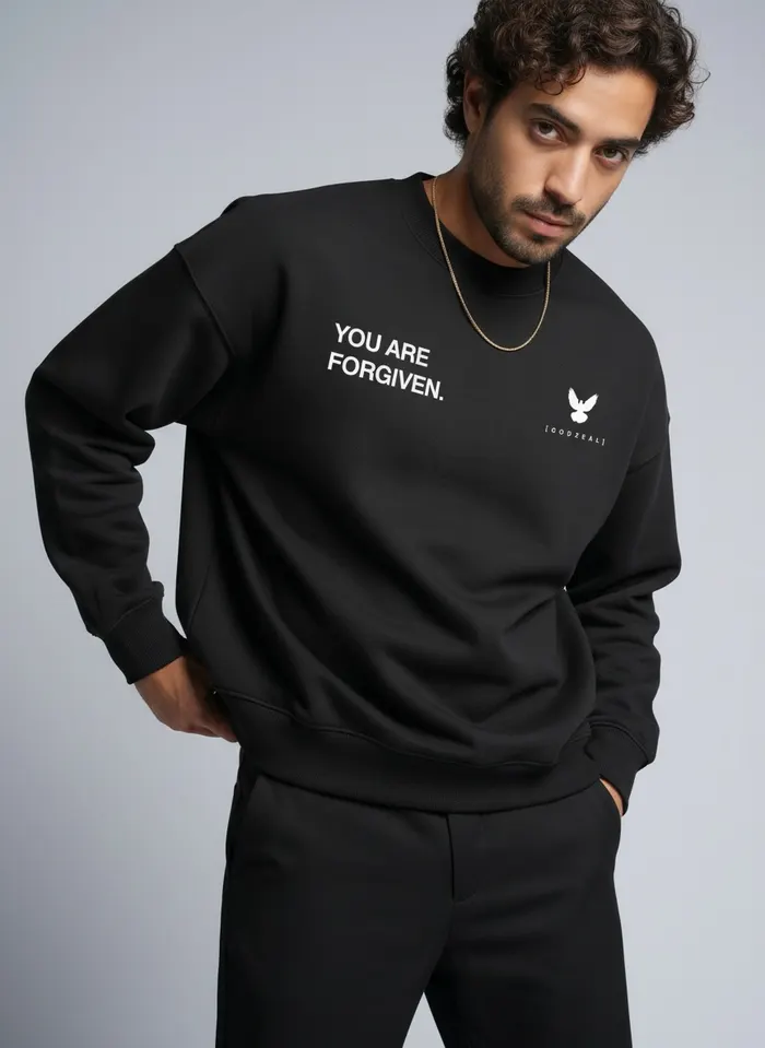 Godzeal YOU ARE FORGIVEN black crewneck sweater alt pose on AI male model with curly hair and gold chain in clean studio