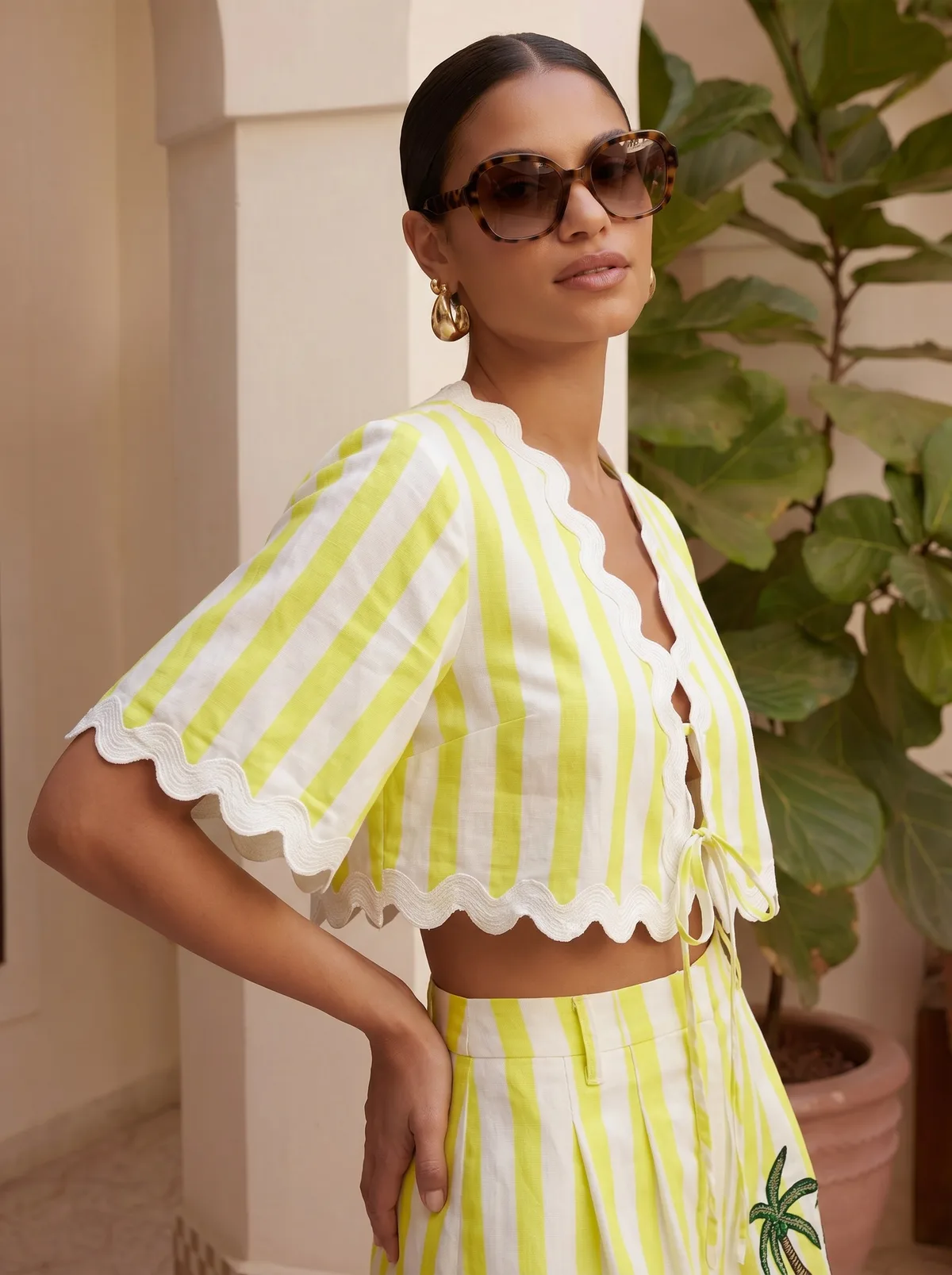Maison Blu lime stripe scallop-edge crop top editorial closeup with oversized tortoiseshell sunglasses on AI model in Moroccan arched courtyard