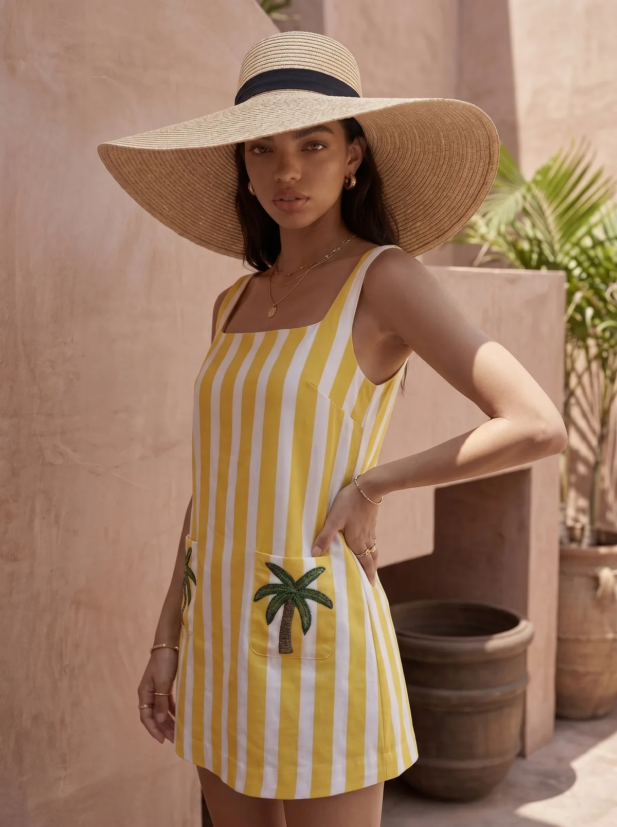 Maison Blu yellow stripe palm-pocket dress editorial closeup under wide-brim straw hat on AI model against terracotta wall with palm fronds