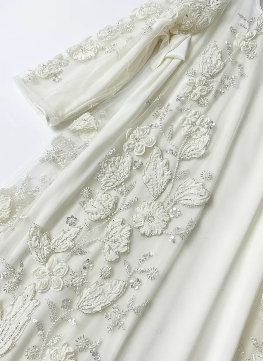 Modest Valoria ivory abaya embroidery macro showing tone-on-tone floral appliqué relief against the satin under-dress