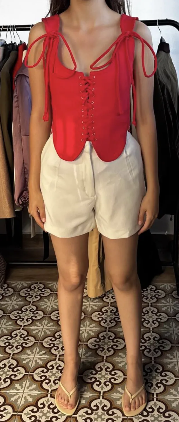 Input showroom photo — the vest top in red on a fit model in the showroom, phone shot