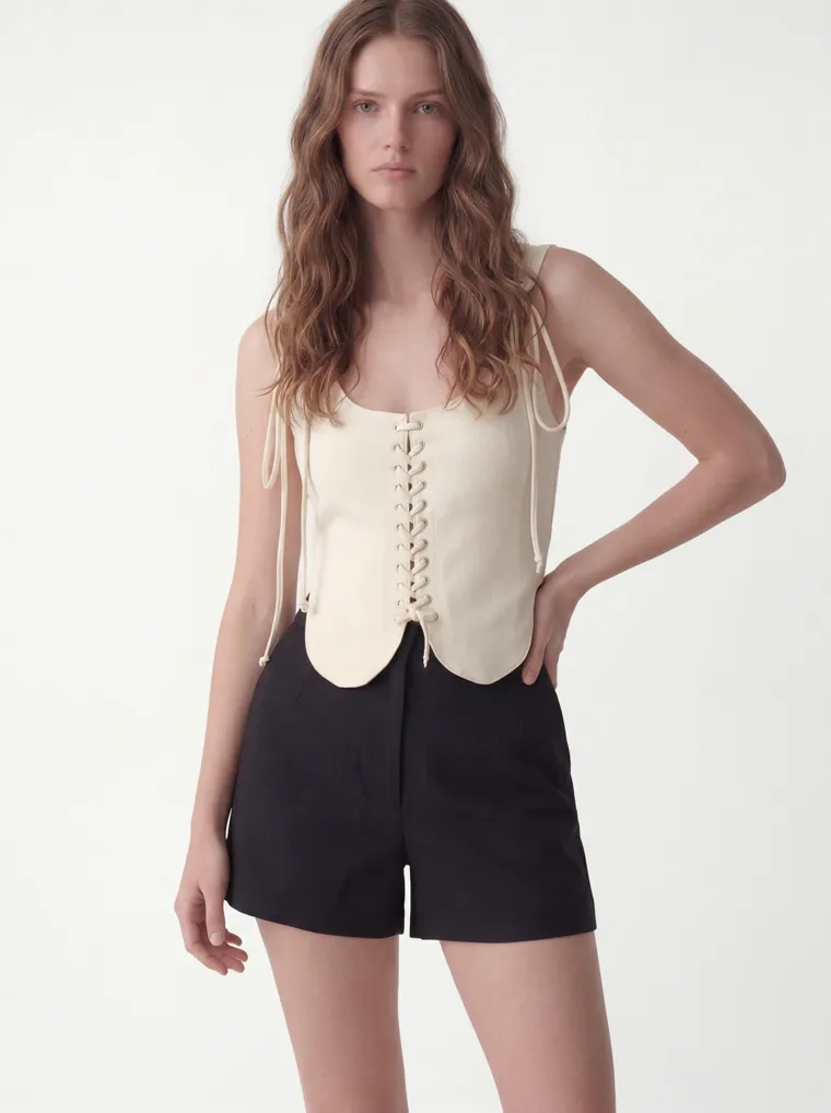 MODA AI catalog output — cream vest top, waist-up detail on the lace-up front