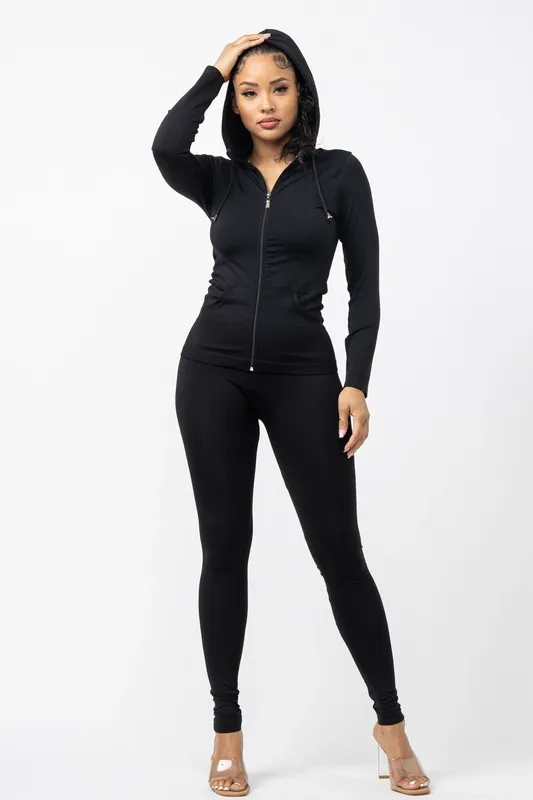Input — generic stock model in black zip-front hoodie and matching leggings against plain white studio background with clear plastic heels, the original catalog photography