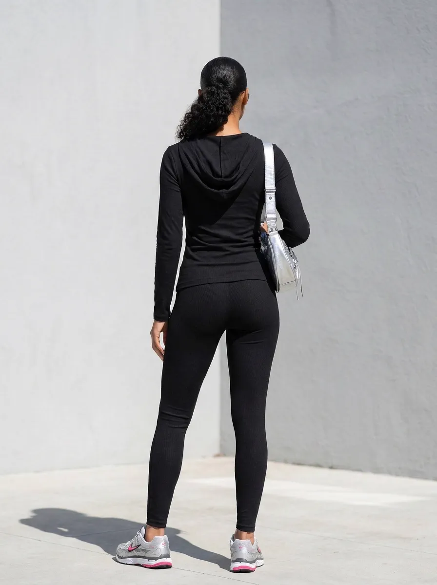 MODA AI recataloging output — back view of same model showing the silver crossbody bag strap and hooded silhouette against urban backdrop
