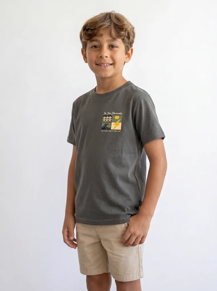 A charcoal boys tee with a surf graphic on the chest and a larger version across the back, worn with stone shorts. FW26 look 18, Graphic Basic in Charcoal, frame 3 of 5