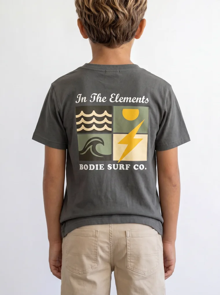 The back of a charcoal boys tee showing a large surf graphic in full, FW26 look 18