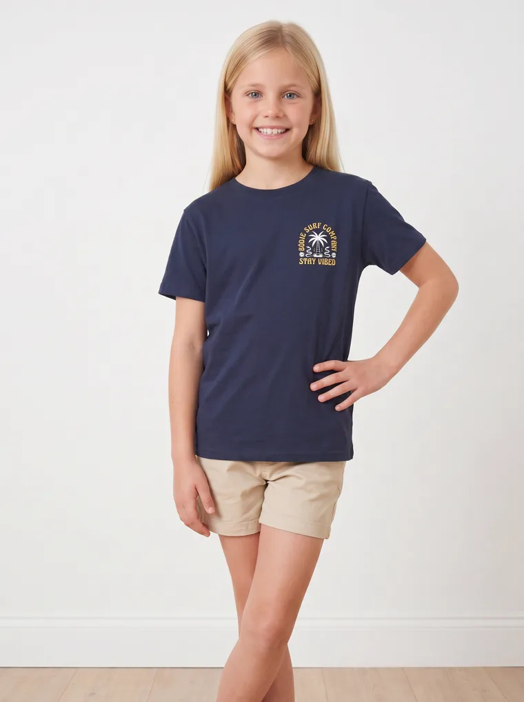 A navy girls tee with a palm and surfboard graphic, worn with stone shorts. FW26 look 19, Graphic Basic in Navy, frame 4 of 5