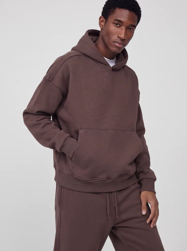 A chocolate brown hooded sweatshirt and matching sweatpants worn as a single tonal set. FW26 look 04