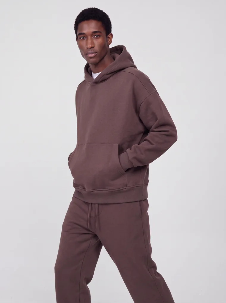 A chocolate brown hooded sweatshirt and matching sweatpants worn as a single tonal set. FW26 look 04, Tonal Set in Chocolate, frame 2 of 5