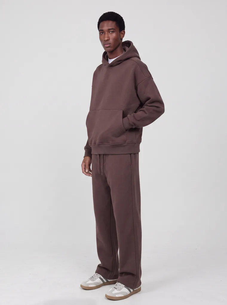 A chocolate brown hooded sweatshirt and matching sweatpants worn as a single tonal set. FW26 look 04, Tonal Set in Chocolate, frame 3 of 5
