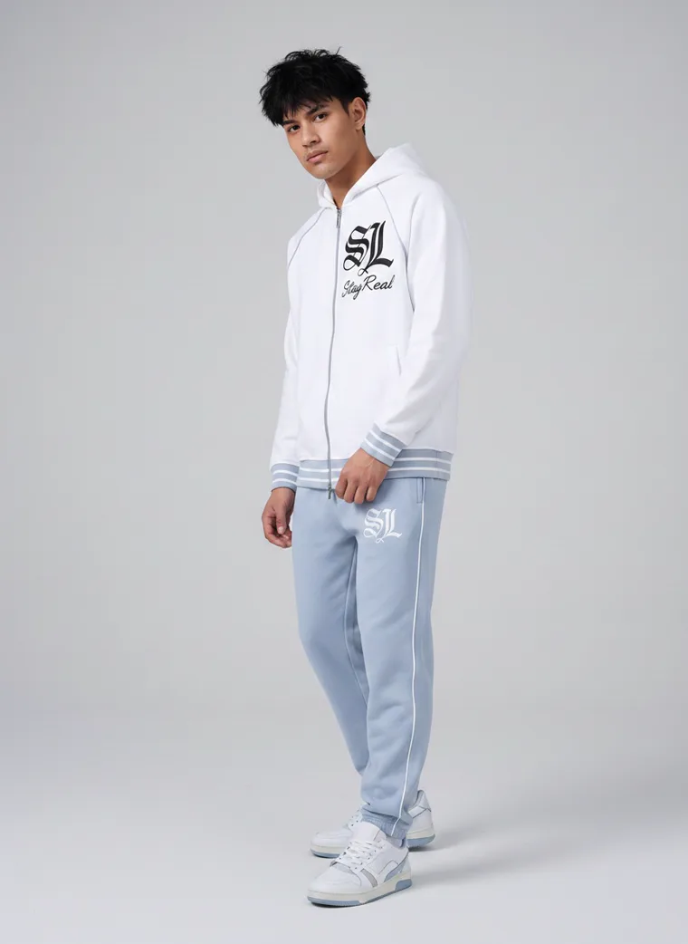 A white zip through hoodie with gothic lettering and a large back print, worn with pale blue sweatpants. FW26 look 05, Graphic Layer in White, frame 3 of 5