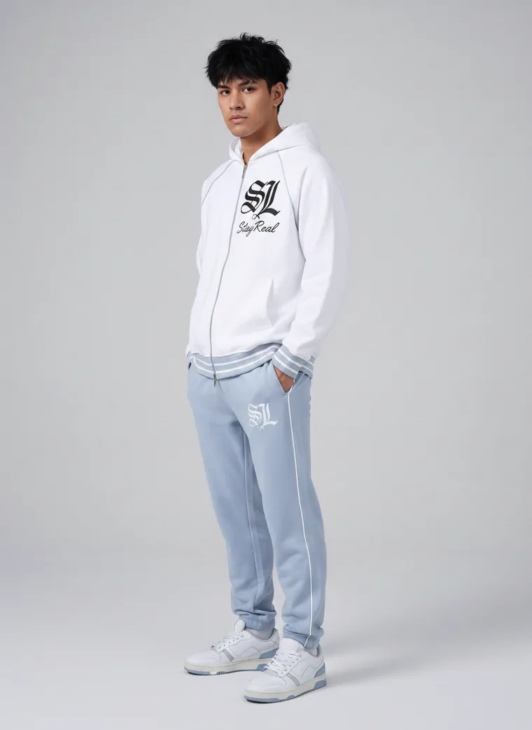 A white zip through hoodie with gothic lettering and a large back print, worn with pale blue sweatpants. FW26 look 05, Graphic Layer in White, frame 4 of 5
