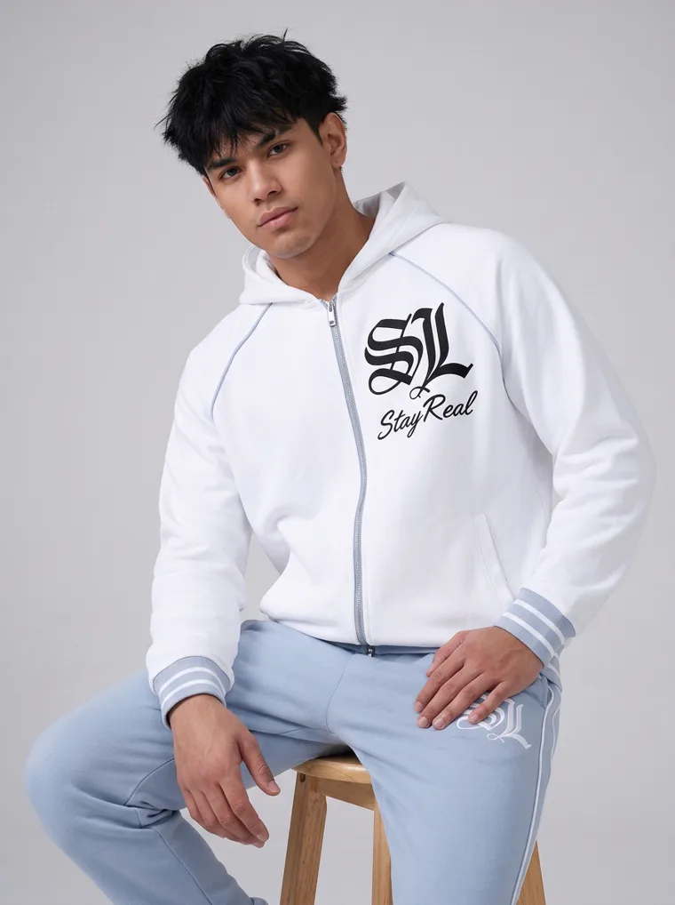 A white zip through hoodie with gothic lettering and a large back print, worn with pale blue sweatpants. FW26 look 05, Graphic Layer in White, frame 5 of 5