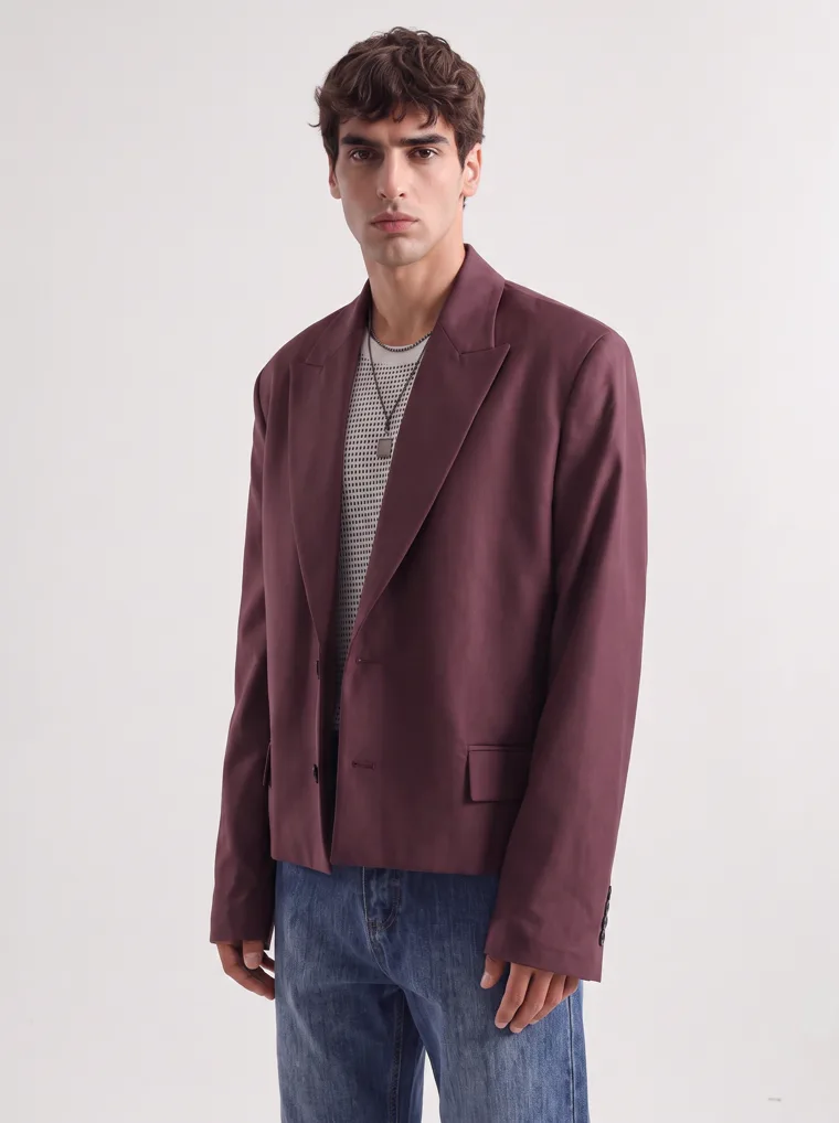 An oversized burgundy blazer over a fine striped knit with straight blue jeans and a burgundy tote. FW26 look 02, Soft Tailoring in Burgundy, frame 4 of 5