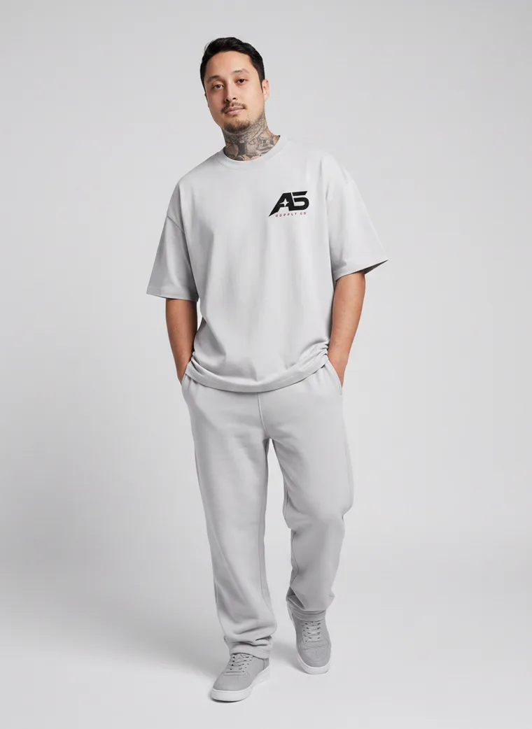 An oversized light grey tee and matching grey sweatpants with a small chest logo and a large back graphic. FW26 look 06, Tonal Sportswear in Grey, frame 2 of 5