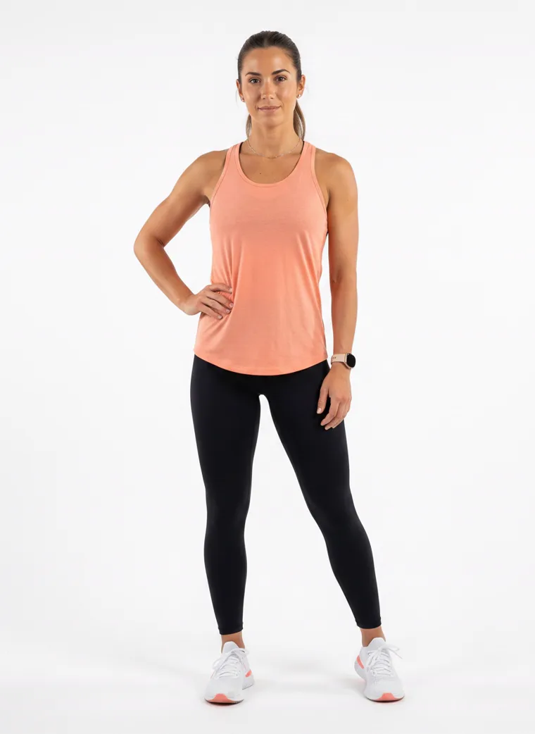 A model in a peach racerback vest with full length black leggings, FW26 look 17