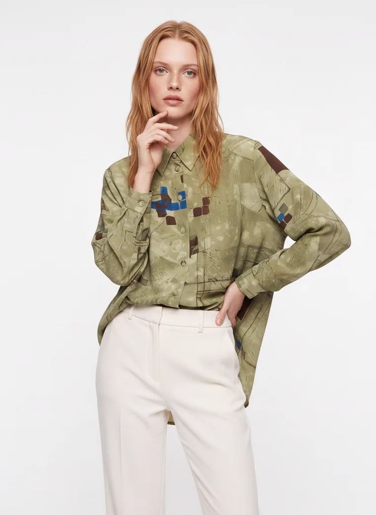 An olive abstract print oversized shirt worn open over cream wide leg trousers. FW26 look 08, Print on Ease in Olive, frame 3 of 5