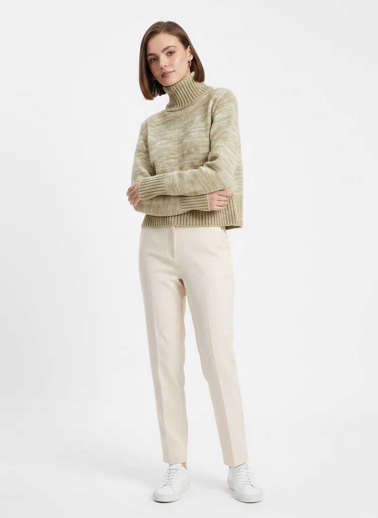 A model in a marled sage green roll neck knit with cream tailored trousers, FW26 look 09