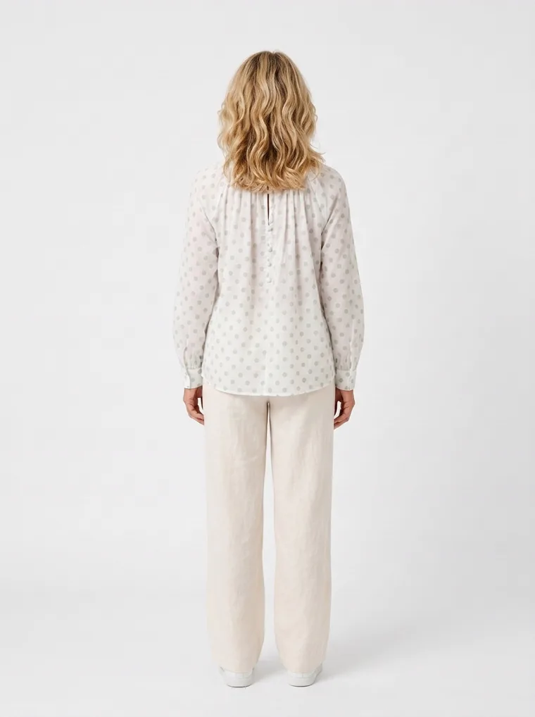 MODA AI on-model output — the white dotted blouse styled with cream trousers, additional catalog angle, generated from a hanger shot in the same clean studio as the rest of the collection