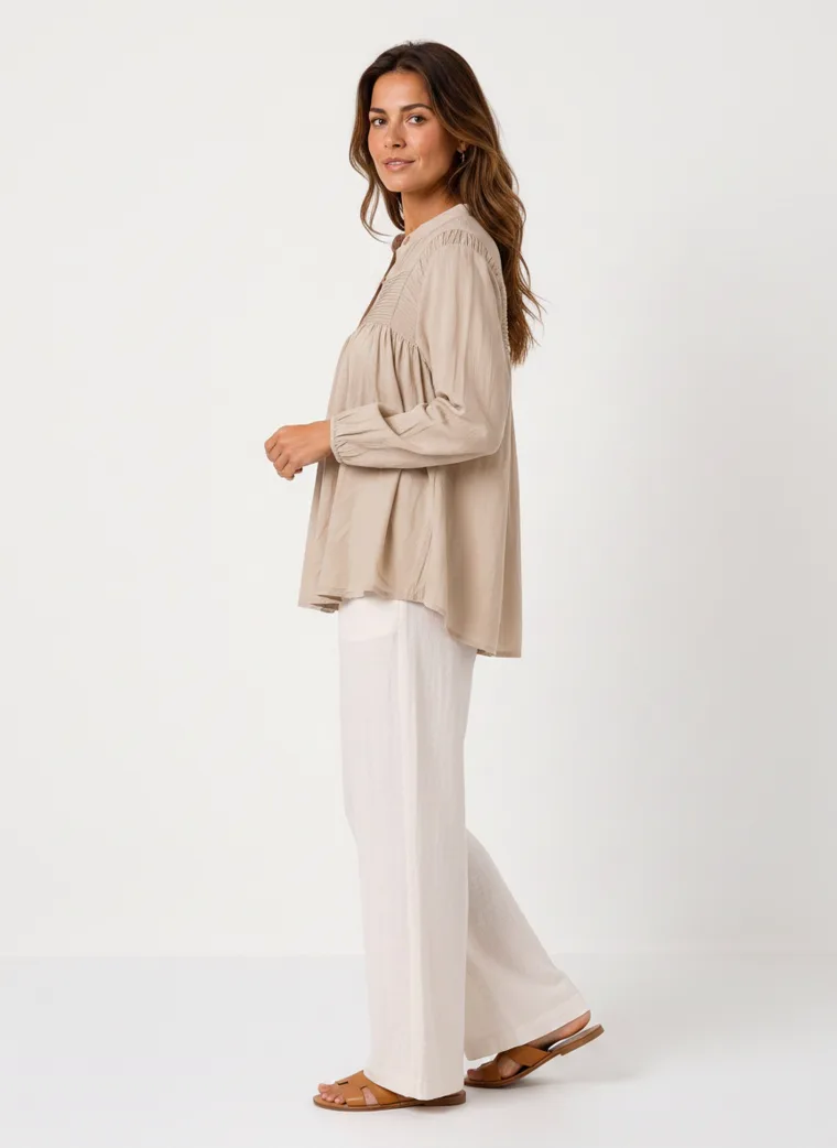 MODA AI on-model output — the oatmeal smock blouse styled with cream wide-leg trousers, additional catalog angle, generated from a hanger shot in the same clean studio as the rest of the collection