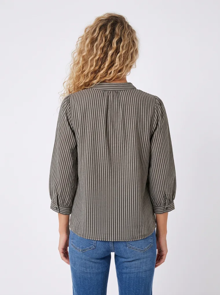 MODA AI on-model output — the striped shirt styled with blue jeans and white trainers, back view, generated from a hanger shot in the same clean studio as the rest of the collection