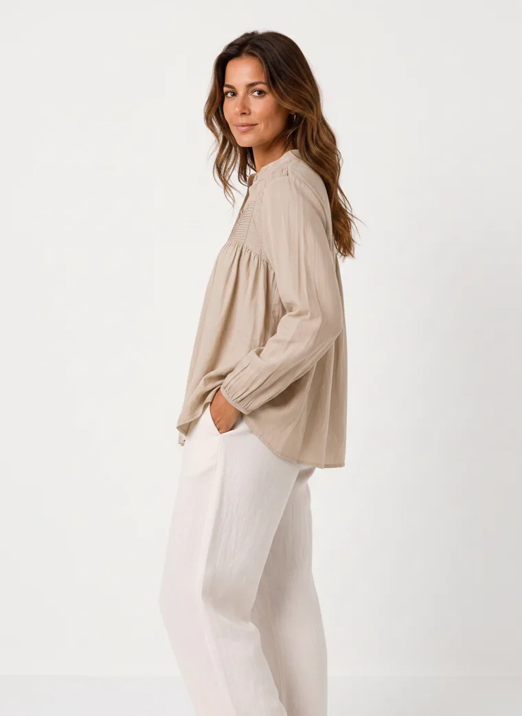 MODA AI on-model output — the oatmeal smock blouse styled with cream wide-leg trousers, additional catalog angle, generated from a hanger shot in the same clean studio as the rest of the collection