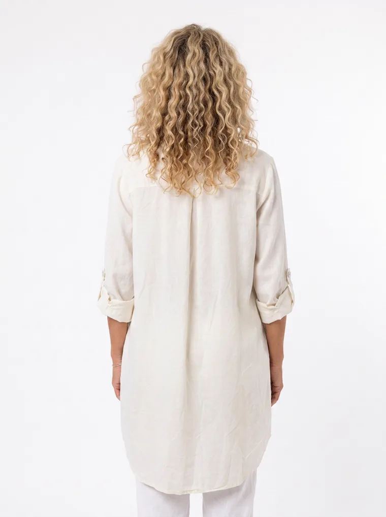 MODA AI on-model output — the cream shirt dress worn over white trousers, back view, generated from a hanger shot in the same clean studio as the rest of the collection