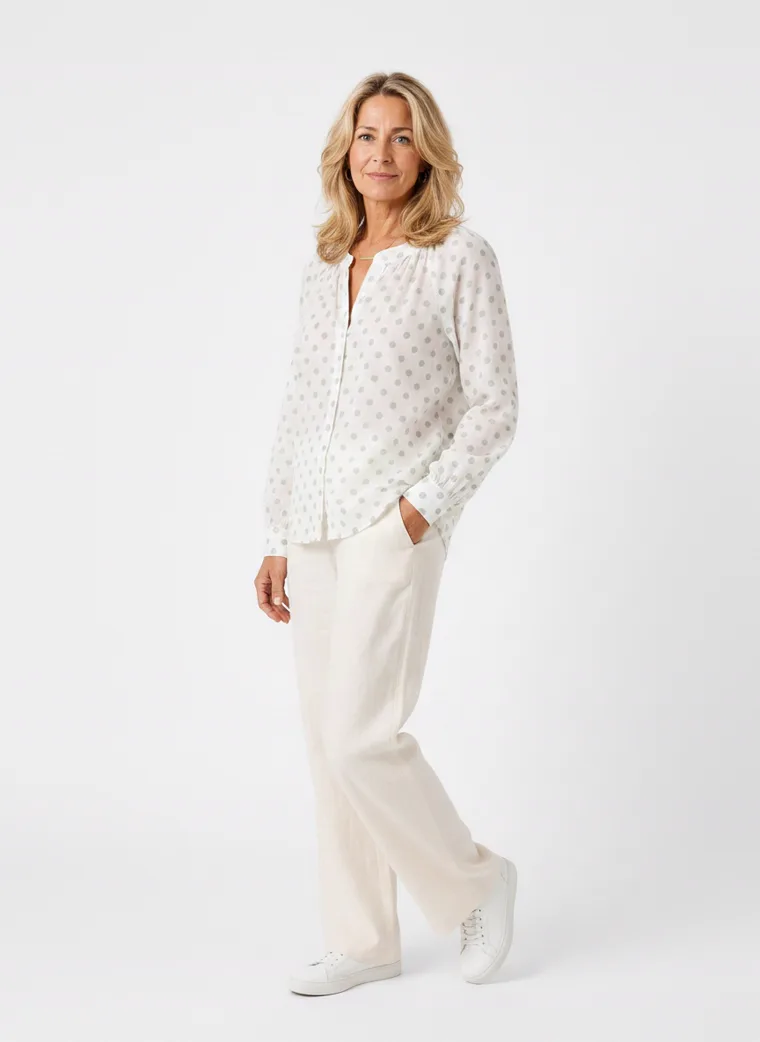 MODA AI on-model output — the white dotted blouse styled with cream trousers, back view, generated from a hanger shot in the same clean studio as the rest of the collection