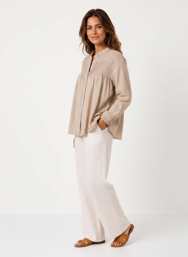 MODA AI on-model output — the oatmeal smock blouse styled with cream wide-leg trousers, additional catalog angle, generated from a hanger shot in the same clean studio as the rest of the collection