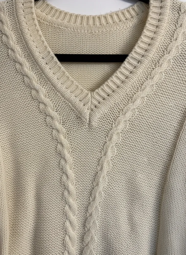 MODA AI output — close-up detail of the cable-knit texture and V-neck ribbing on the cream jumper