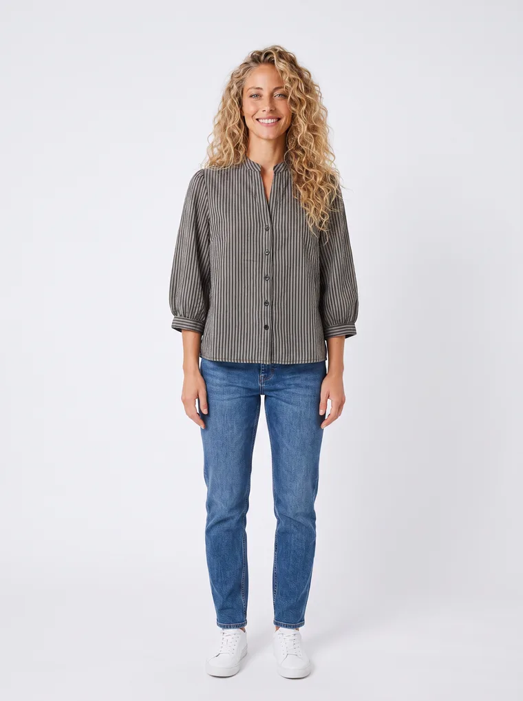 MODA AI output — a woman wearing the striped shirt with blue jeans and white trainers in a clean studio