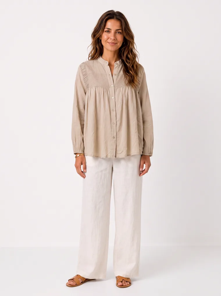 MODA AI output — a dark-haired woman wearing the oatmeal smock blouse with cream wide-leg trousers