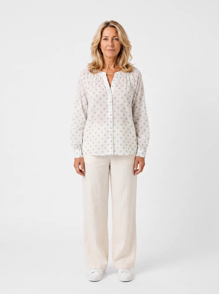 MODA AI output — a woman wearing the white dotted blouse with cream trousers and white trainers
