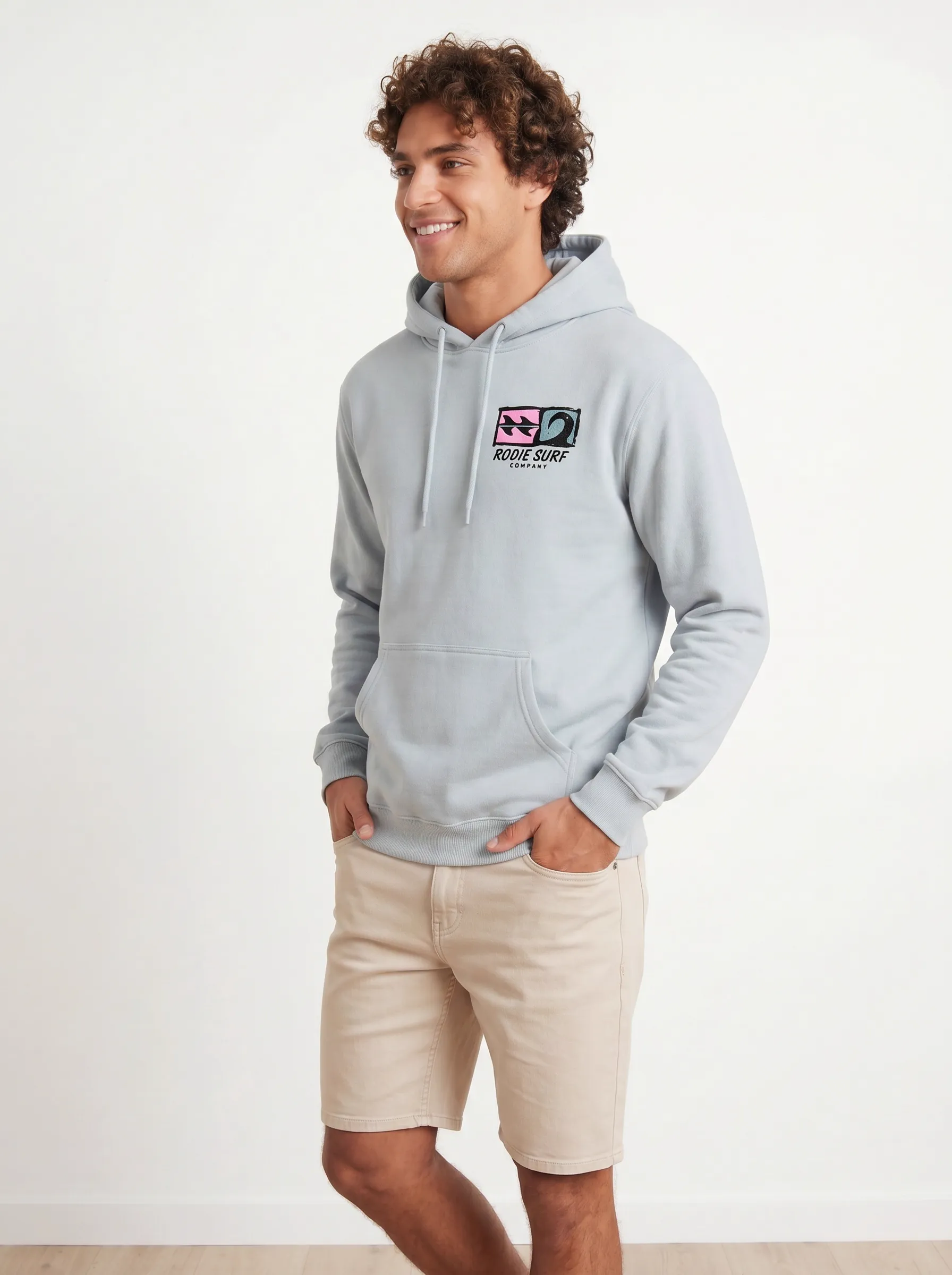 MODA AI back view — light blue hoodie with quilt-block four-quadrant logo in pink, teal, and black with Bödie Surf Company script