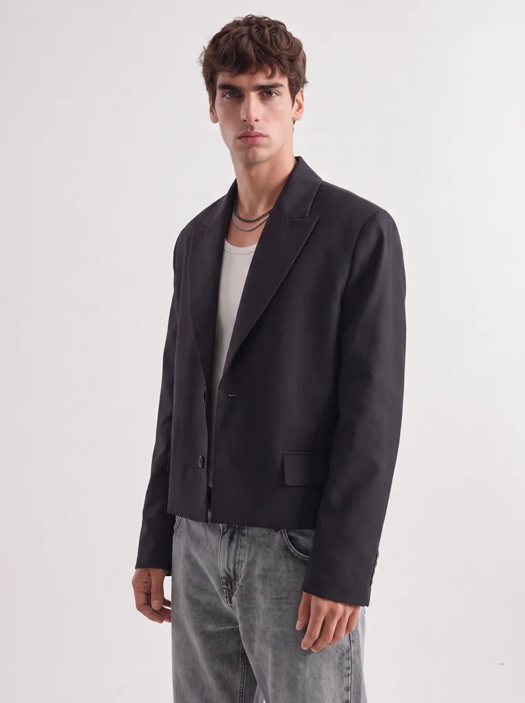 A black relaxed blazer over a cream tank with washed grey jeans and black boots on white. Relaxed Blazer in Black, frame 2 of 5