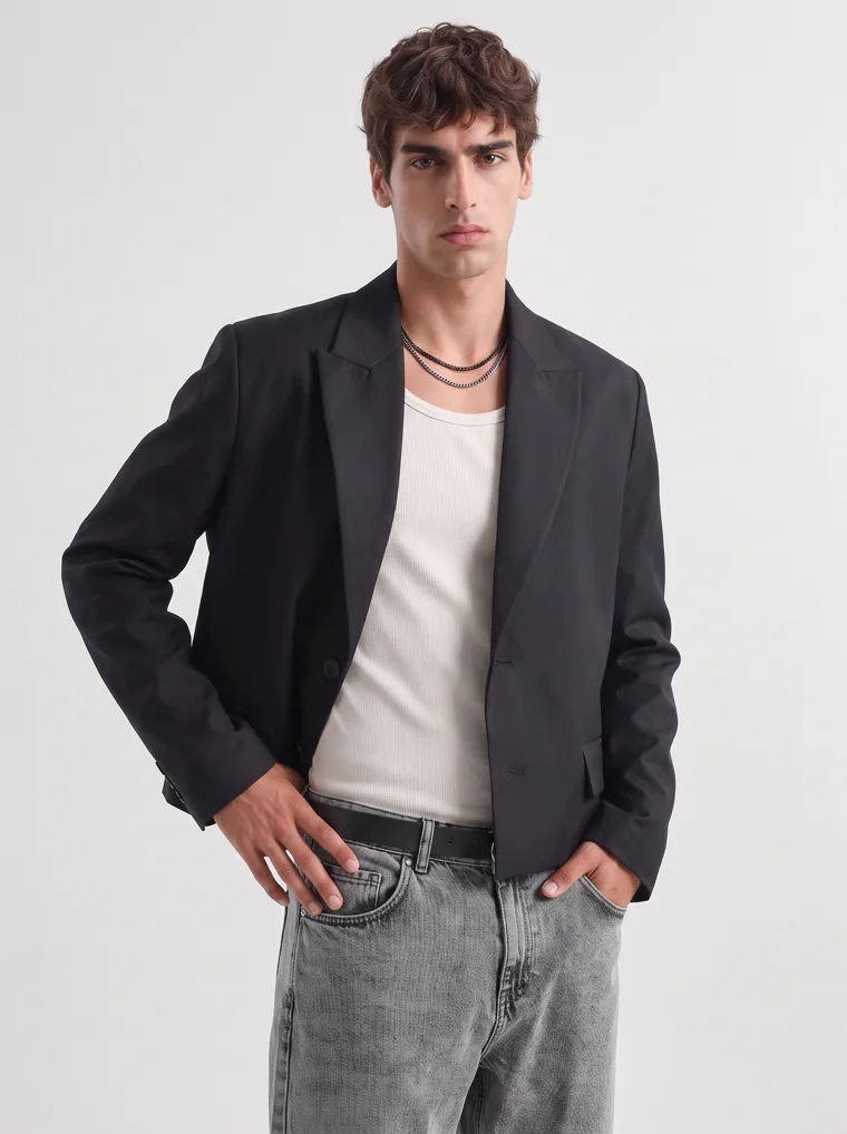 A black relaxed blazer over a cream tank with washed grey jeans and black boots on white. Relaxed Blazer in Black, frame 3 of 5