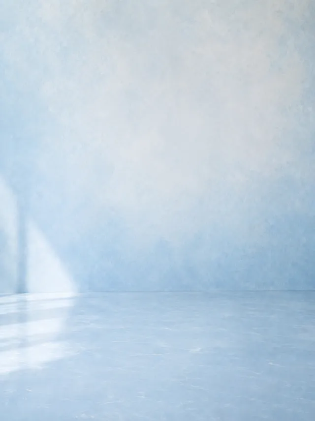 A soft blue painted studio wall with light falling across a pale floor, supplied as the background reference for the whites set