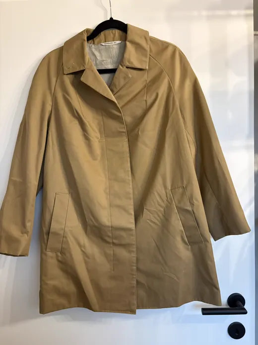 The starting photo for Car Coat in Camel: the coat on a hanger by a door