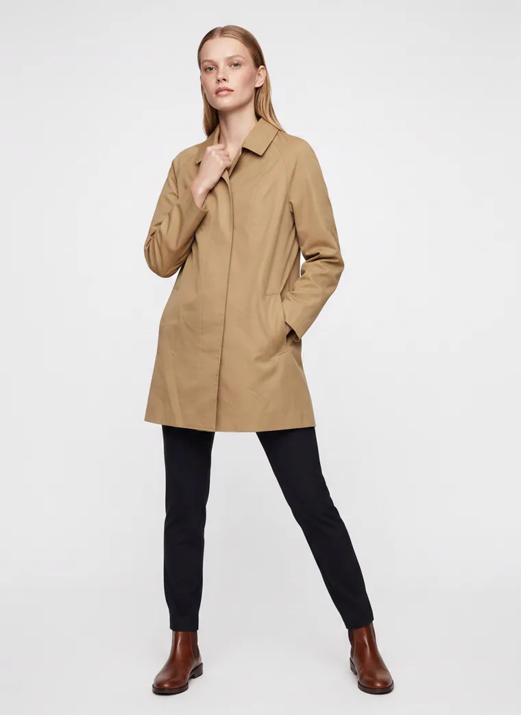 A camel car coat worn with black slim trousers and brown ankle boots on pale grey. Car Coat in Camel, frame 4 of 5