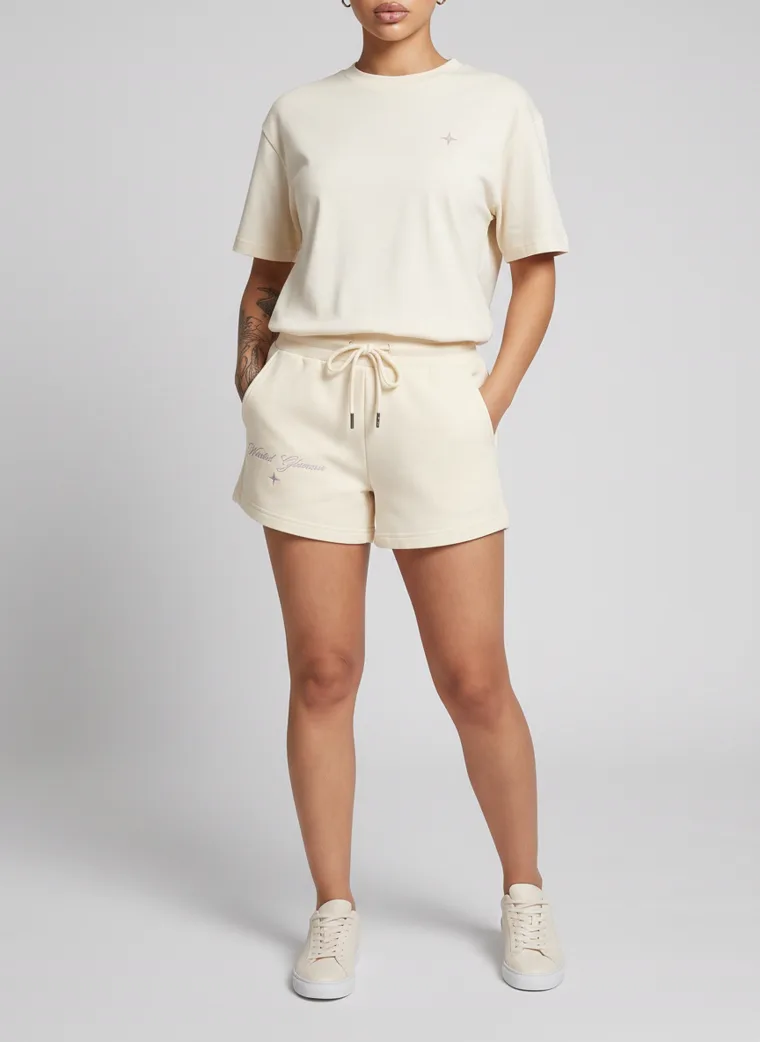 Cream drawstring sweat shorts styled with a matching boxy tee and cream sneakers on pale grey. Drawstring Shorts in Cream, frame 2 of 5