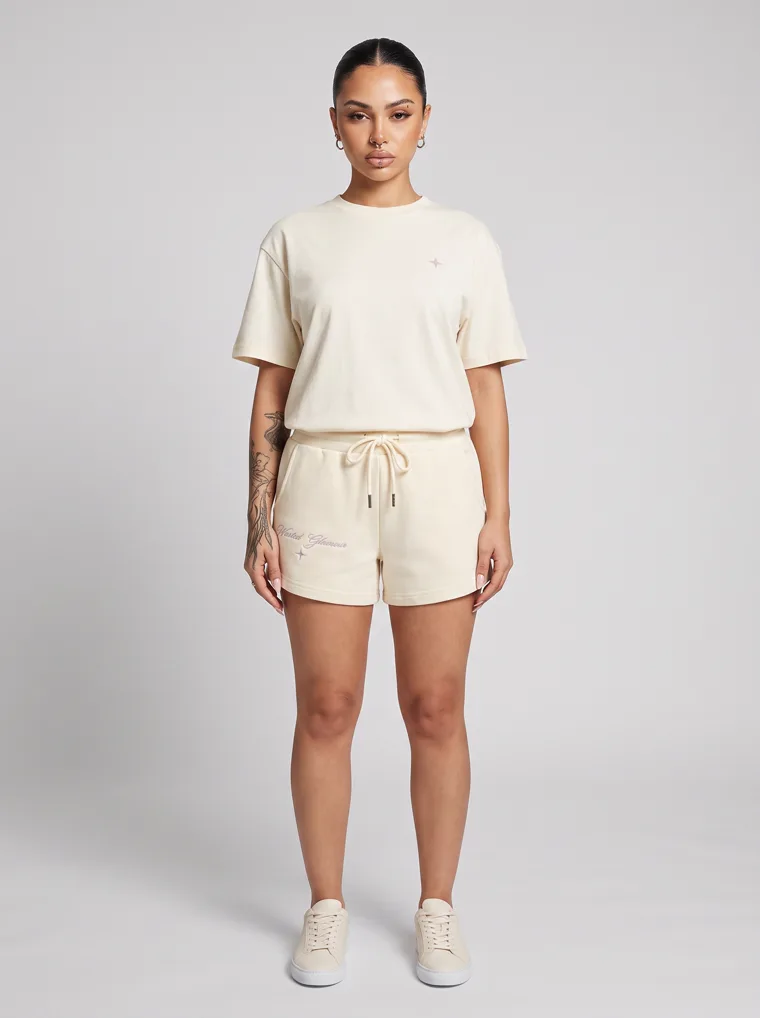 Cream drawstring sweat shorts styled with a matching boxy tee and cream sneakers on pale grey. Drawstring Shorts in Cream, frame 5 of 5